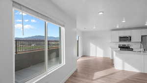 Kitchen featuring white cabinets, stainless steel appliances, light wood-style flooring, a mountain view, and recessed lighting