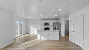 Kitchen with white cabinets, a kitchen island with sink, light wood-type flooring, stainless steel appliances, and recessed lighting