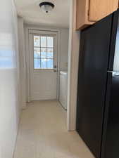 Doorway to outside with a textured ceiling, washer / clothes dryer, and tile patterned floors