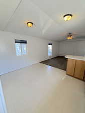 Unfurnished living room featuring a textured ceiling, light flooring, and ceiling fan