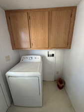 Laundry room featuring cabinet space, washer / dryer, and a textured ceiling