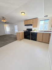 Kitchen with a peninsula, a textured ceiling, light countertops, black appliances, and open floor plan