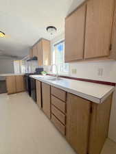 Kitchen with a peninsula, light flooring, light countertops, gas stove, and under cabinet range hood