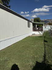 View of green lawn with a mountain view and a patio