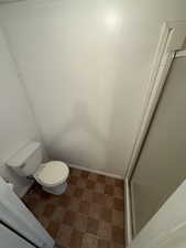 Bathroom with a shower stall, baseboard heating, and tile patterned floors