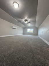 Bonus room with vaulted ceiling, a textured ceiling, carpet flooring, and a ceiling fan