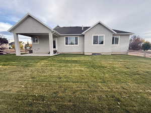 Back of property featuring stucco siding, a patio, a lawn, and roof with shingles