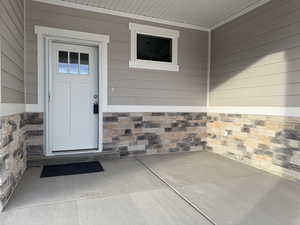 Entrance to property featuring stone siding and a patio