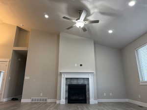 Unfurnished living room featuring vaulted ceiling, light wood-style floors, a tile fireplace, ceiling fan, and recessed lighting