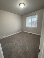 Carpeted spare room featuring a textured ceiling and baseboards