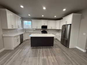 Kitchen with white cabinetry, recessed lighting, appliances with stainless steel finishes, a center island, and light wood-type flooring