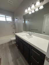 Full bathroom with vanity, dark wood-style floors, and bathtub / shower combination