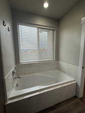 Bathroom with wood finished floors, a garden tub, and recessed lighting