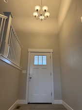 Doorway to outside with a chandelier and wood finished floors