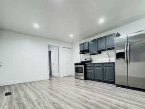 Kitchen with stainless steel appliances, light wood-style flooring, recessed lighting, open floor plan, and light countertops