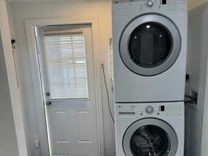 Laundry area featuring estacked washer and dryer, light tile patterned flooring, and a textured wall