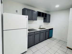 Kitchen featuring freestanding refrigerator, light countertops, light tile patterned flooring, dishwashing machine, and recessed lighting