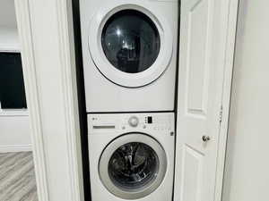 Laundry area featuring stacked washer / drying machine and light wood-type flooring
