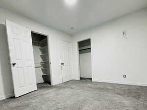 Unfurnished bedroom featuring carpet flooring and two closets