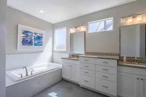 Full bathroom featuring two vanities, a bath, and recessed lighting