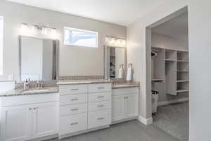 Full bathroom with a walk in closet, two vanities, light tile patterned floors, and light colored carpet