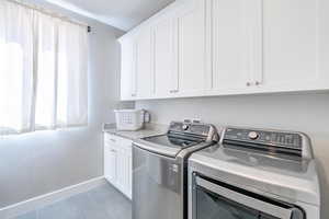 Laundry room with cabinet space, washing machine and clothes dryer, and light tile patterned floors