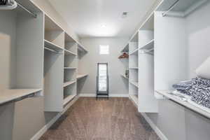 Walk in closet with dark colored carpet