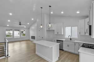 Kitchen with a kitchen island, vaulted ceiling, white cabinets, hanging light fixtures, and recessed lighting