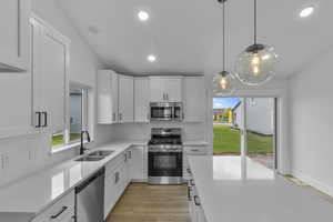 Kitchen with stainless steel appliances, backsplash, white cabinetry, and recessed lighting