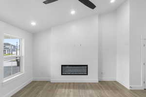 Unfurnished living room featuring a glass covered fireplace, recessed lighting, wood finished floors, and a ceiling fan