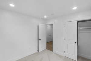 Unfurnished bedroom with light colored carpet, recessed lighting, and a closet