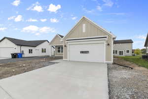 View of front of property with board and batten siding, driveway, and a garage