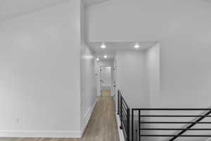 Corridor featuring light wood-style flooring, recessed lighting, and an upstairs landing