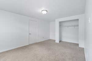 Unfurnished bedroom with light carpet and a closet