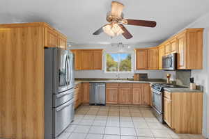 Kitchen with stainless steel appliances, light tile patterned floors, rail lighting, and ceiling fan