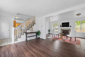 Living room with a textured ceiling, wood finished floors, plenty of natural light, stairway, and a tiled fireplace