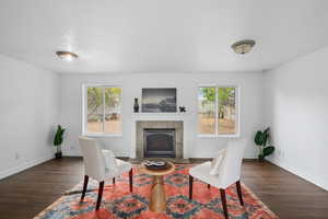 Sitting room with a tile fireplace, dark wood-type flooring, a textured ceiling, and ornamental molding