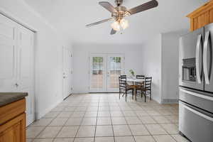 Dining area featuring light tile patterned flooring, crown molding, french doors, and ceiling fan