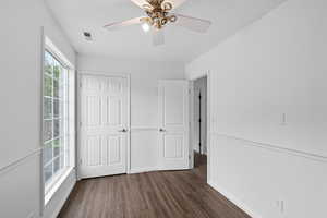 Unfurnished bedroom with dark wood-style floors and a ceiling fan