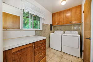 Laundry room with cabinet space, light tile patterned floors, and tile walls