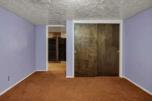 Unfurnished bedroom featuring carpet, a closet, and a textured ceiling