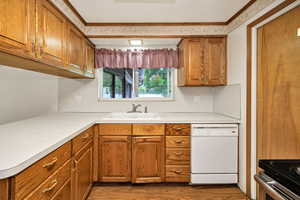 Kitchen featuring brown cabinetry, white dishwasher, light countertops, dark wood-style floors, and range with electric cooktop