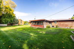Back of property with a family room, a lawn, and brick siding