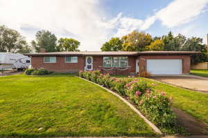 Ranch-style home featuring brick siding, driveway, an attached garage, and a chimney