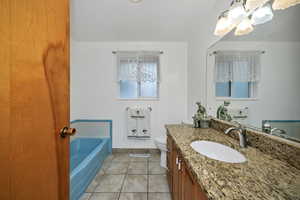 Bathroom featuring light tile patterned floors, a garden tub, and vanity