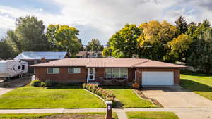 Ranch-style house featuring a metal roof, a front yard, brick siding, and driveway