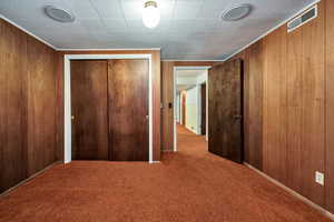 Unfurnished bedroom featuring wood walls, carpet floors, and a closet