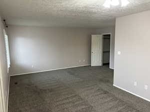 Unfurnished room with dark colored carpet and a textured ceiling