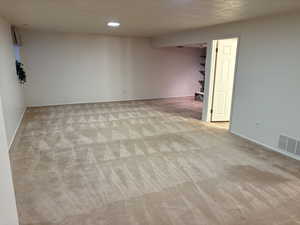 Finished below grade area featuring light carpet, a textured ceiling, and recessed lighting