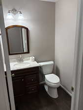 Half bathroom with dark wood-type flooring and vanity